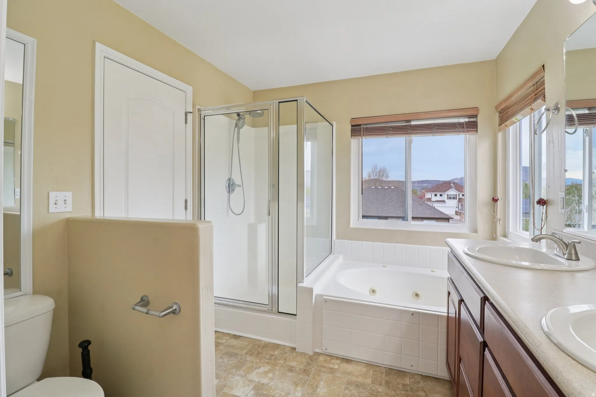 Full bathroom featuring double vanity, a shower stall, and a jetted tub