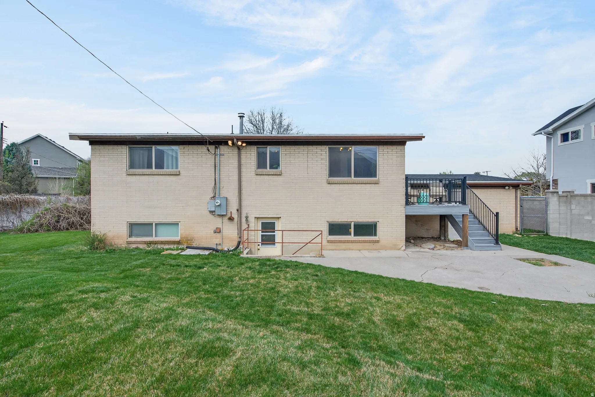 Back of house featuring brick siding, a deck, and a patio area