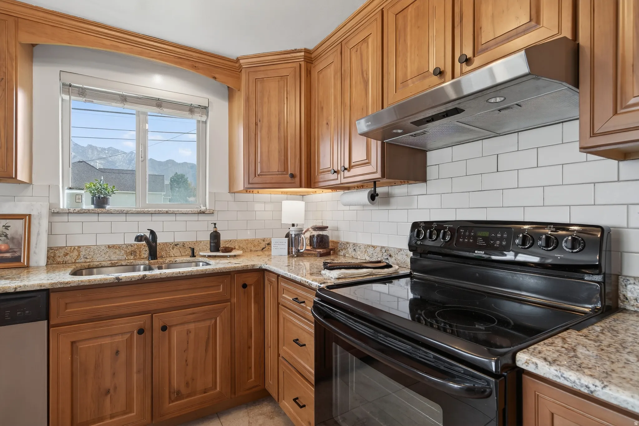 Kitchen with electric range, granite countertops, dishwasher, and wood finish cabinets