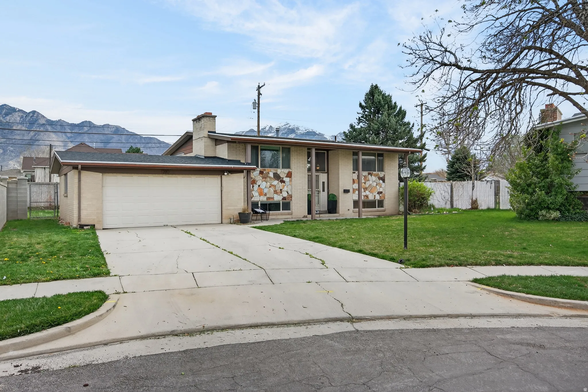 View of front of property featuring brick siding, driveway, a garage, a mountain view, and a chimney