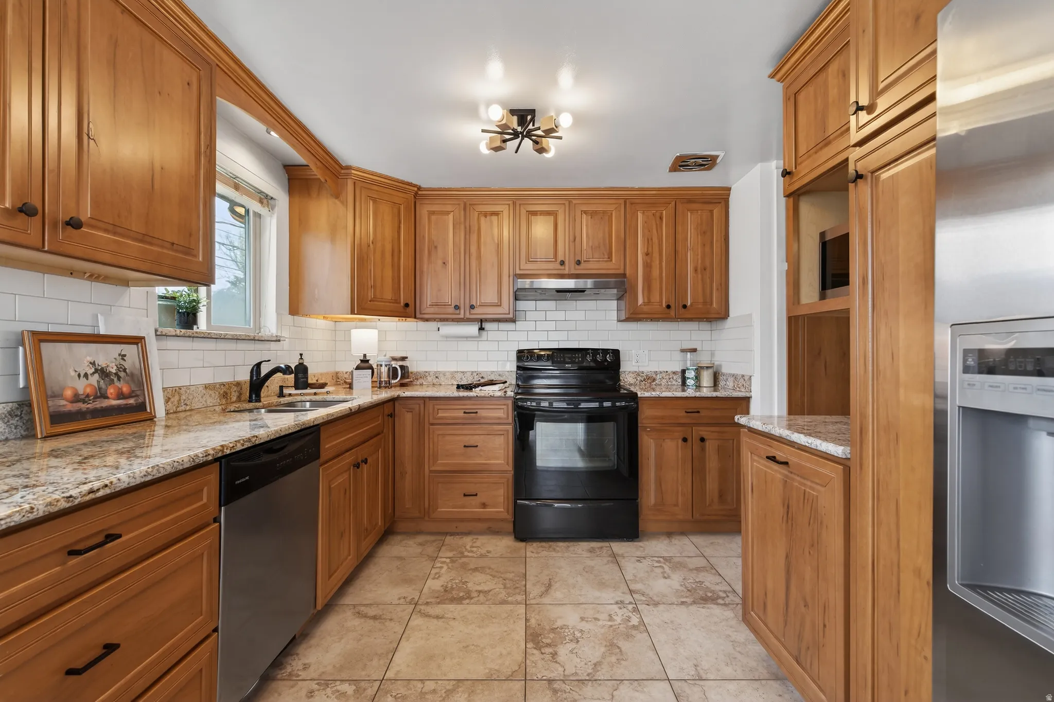 Kitchen with stainless steel appliances, wood finish cabinets, granite countertops, and tasteful backsplash