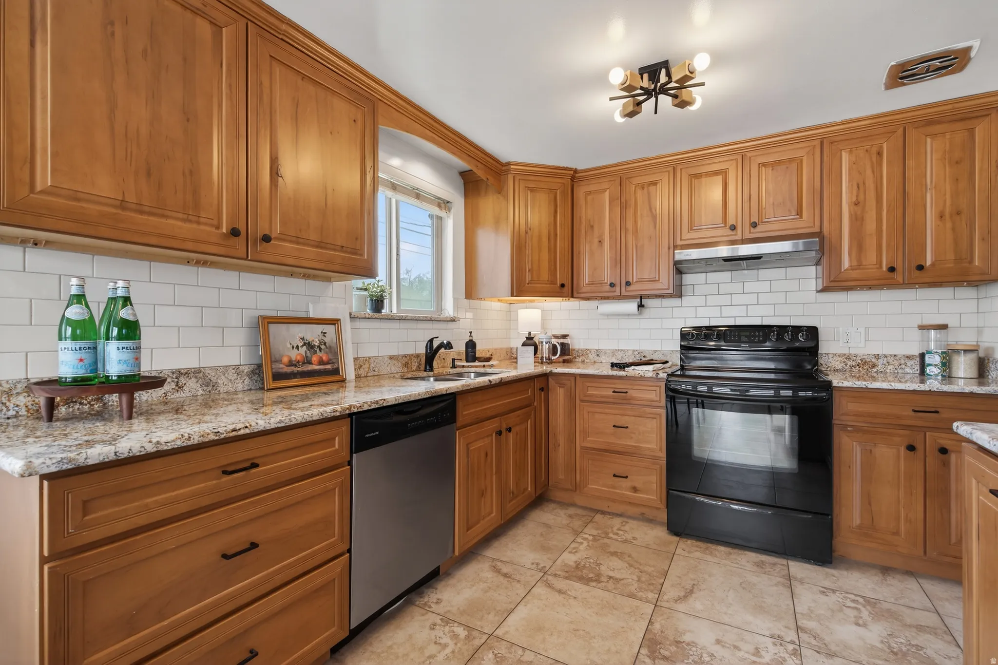 Kitchen featuring black / electric stove, wood finish cabinets, lgranite counters, stainless steel dishwasher, and subway tile backsplash