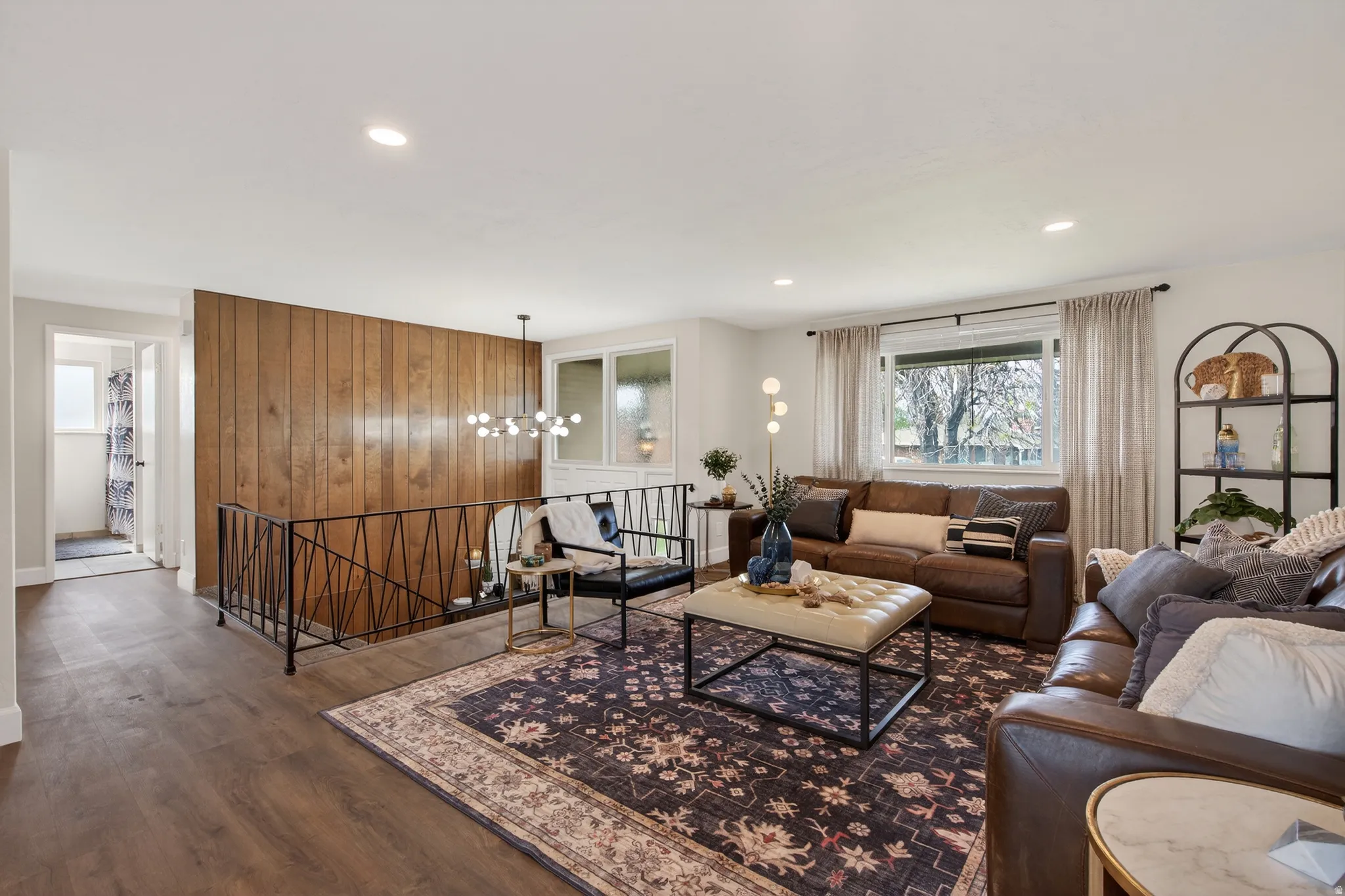 Living room with a chandelier, dark wood-style flooring, and wood wall