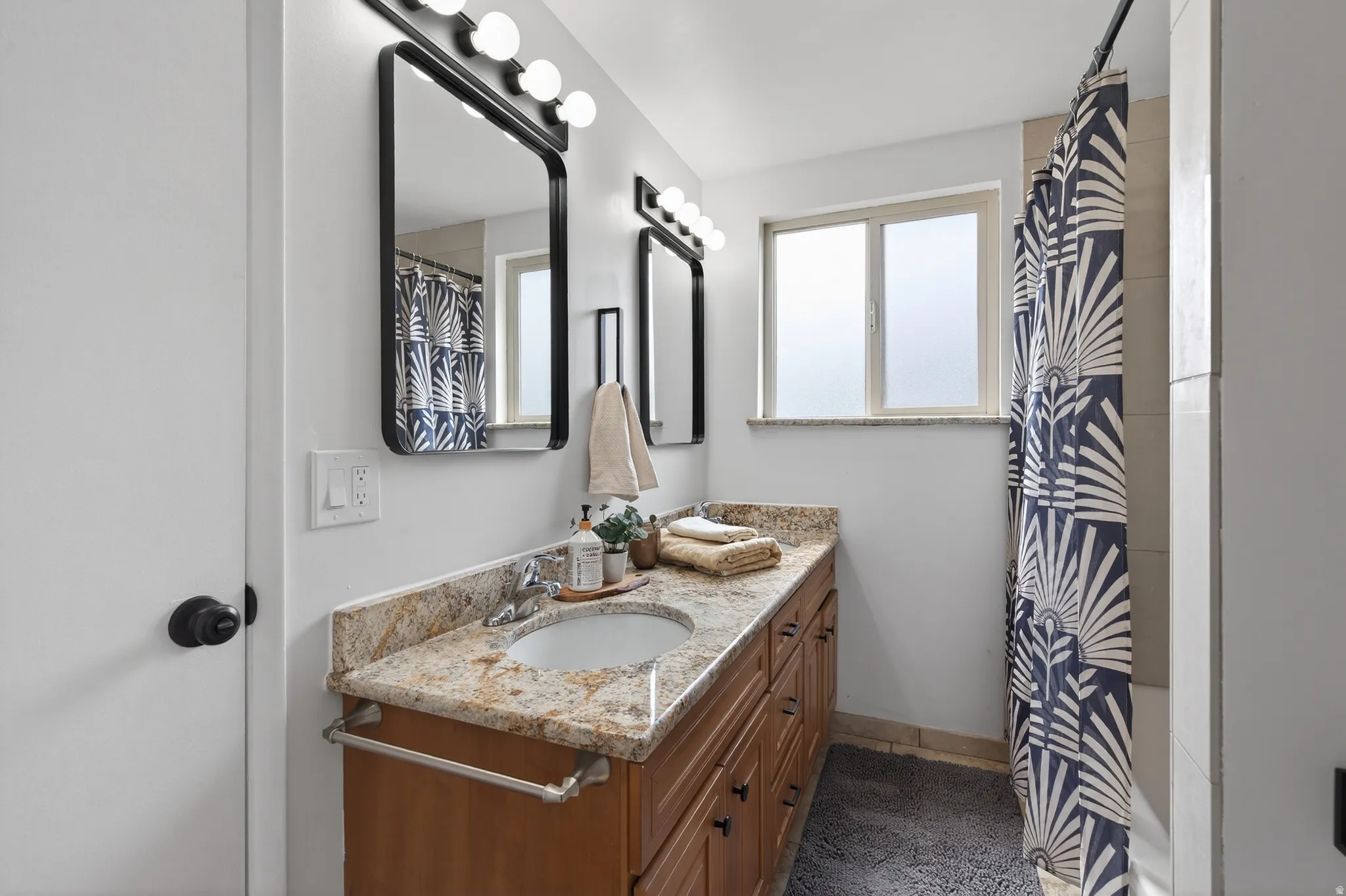 Full bath with curtained shower and double vanity with granite countertops