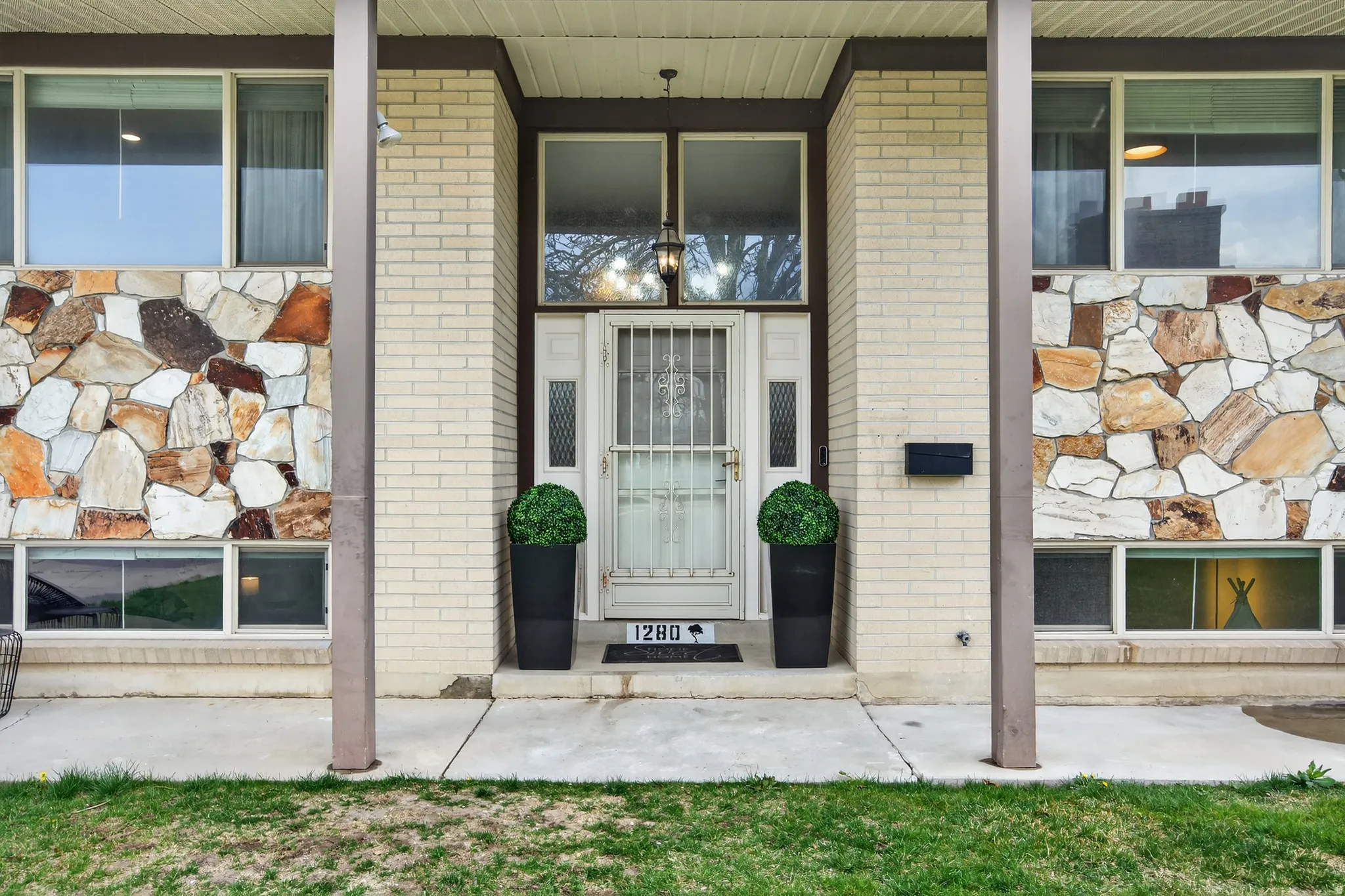 View of exterior entry featuring brick siding and covered porch