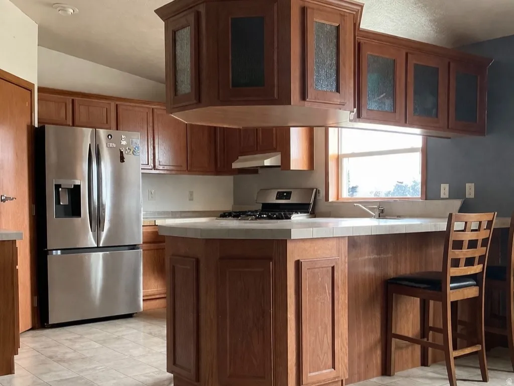 Kitchen with tile countertops, stainless steel appliances, and wood finish cabinetry