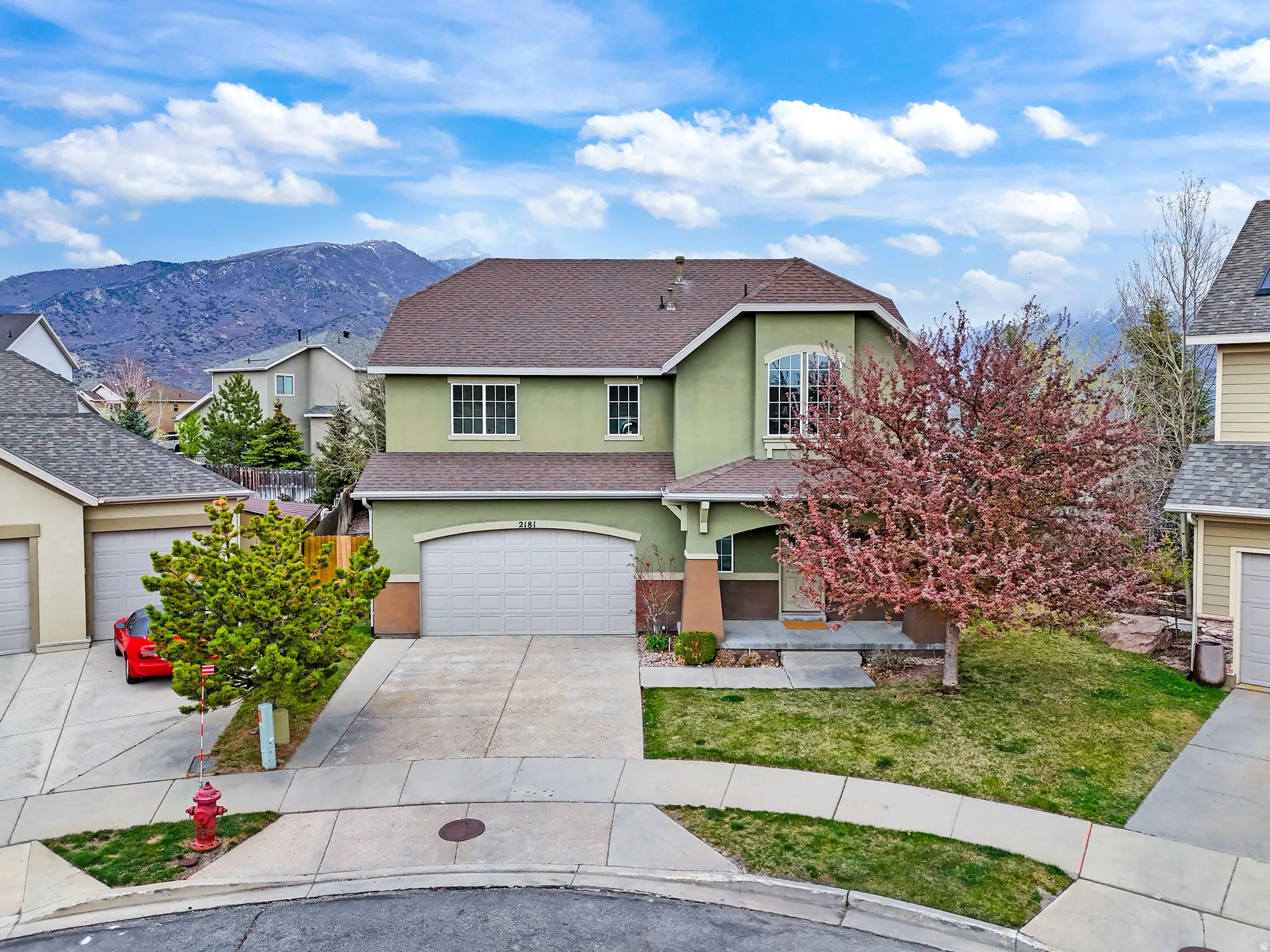 Traditional-style house featuring stucco siding, a mountain view, driveway, a shingled roof, and a garage