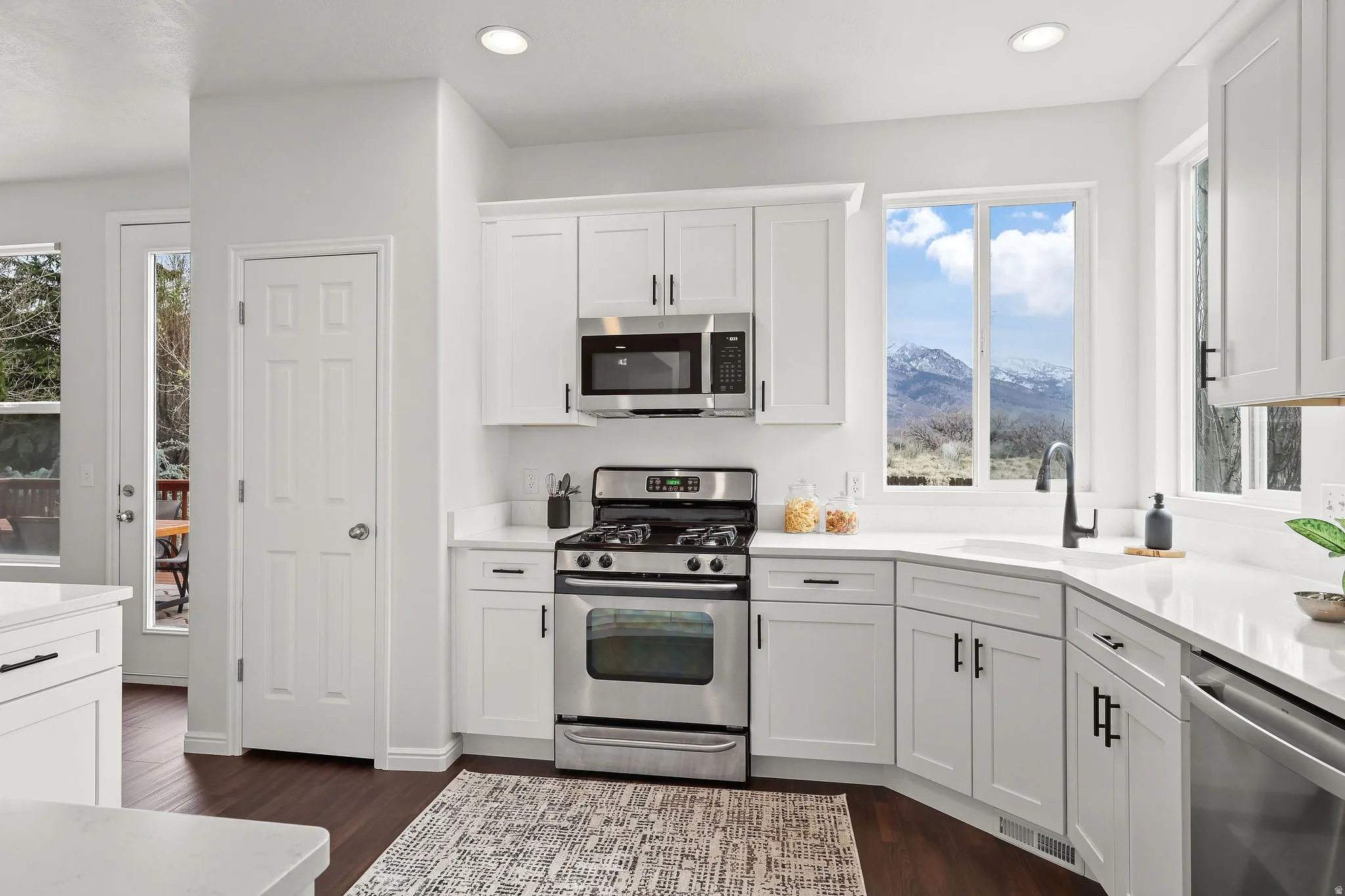 Kitchen featuring white cabinetry, stainless steel appliances, dark wood-style floors, recessed lighting, and light stone countertops
