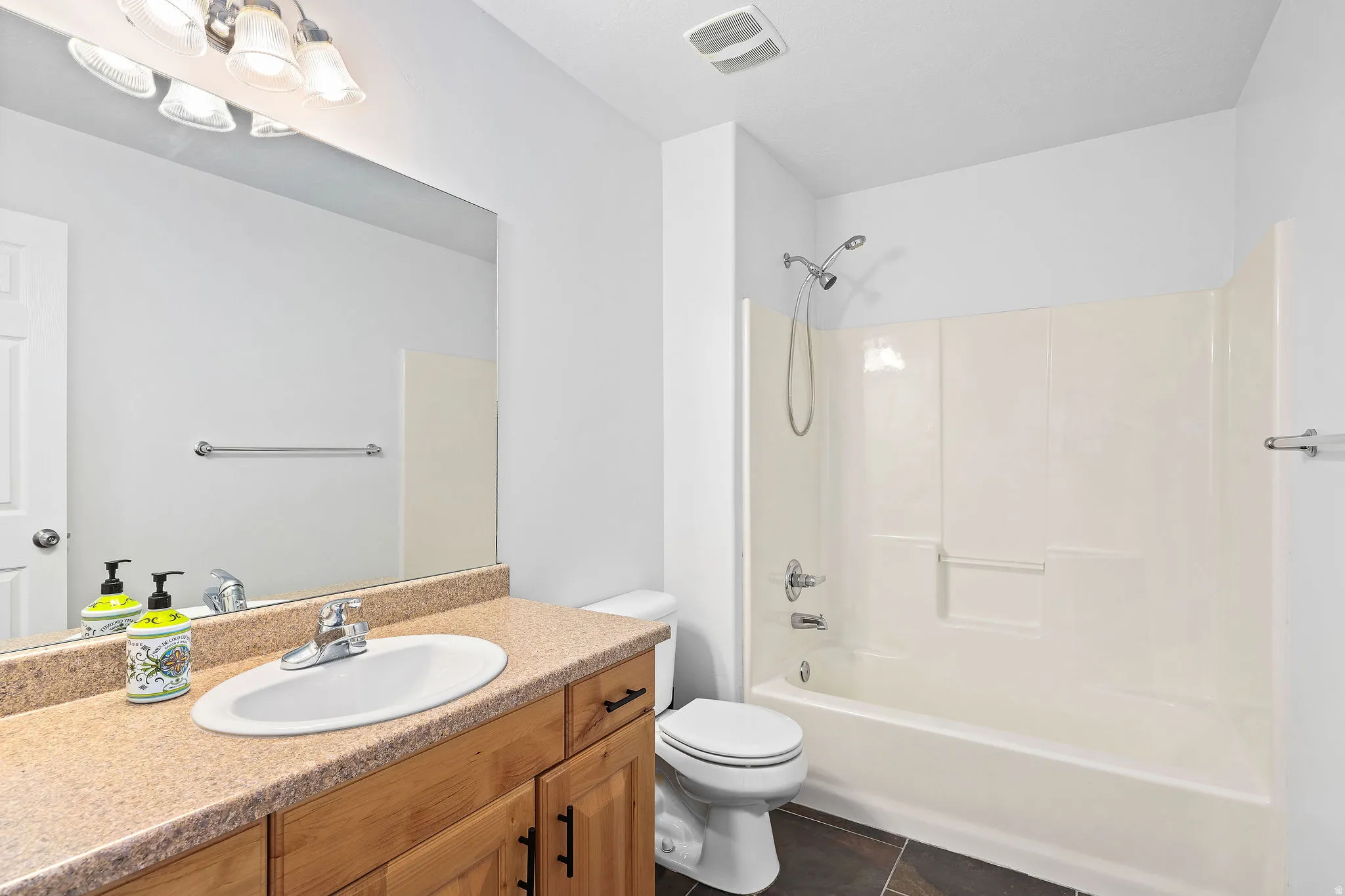 Full bath featuring vanity, shower / washtub combination, and dark tile patterned flooring