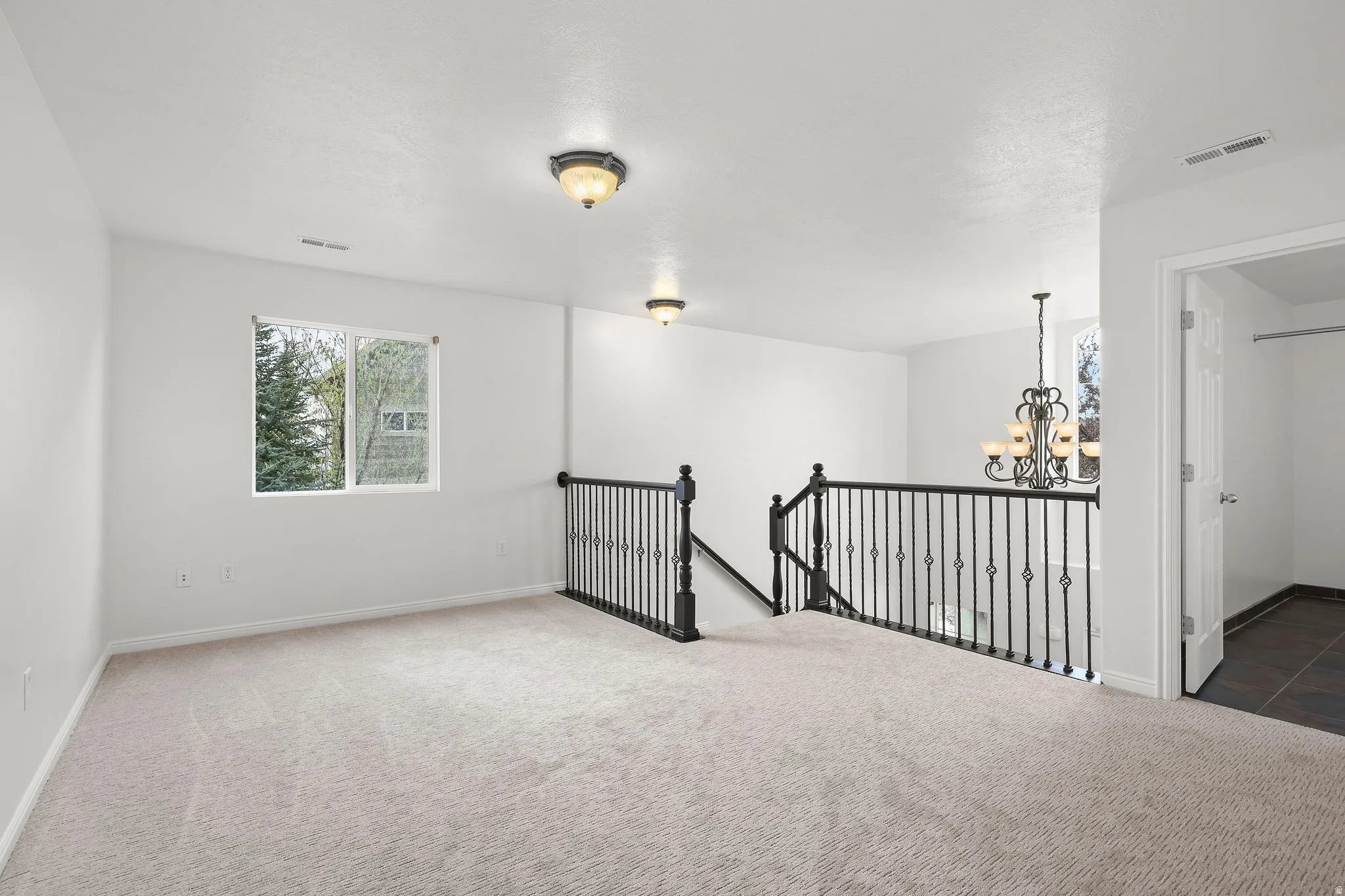 Carpeted spare room featuring suspended lighting and baseboards