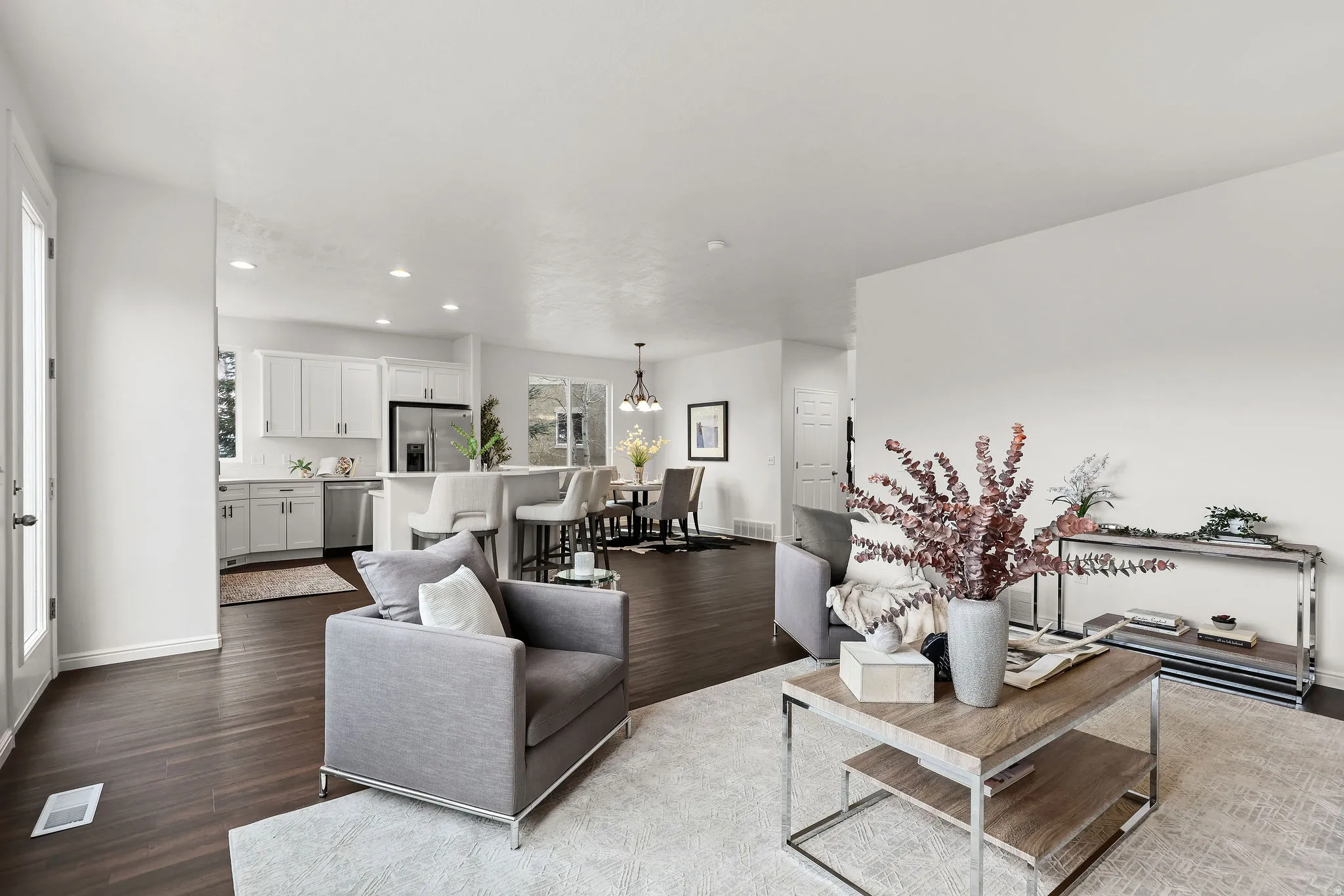 Living room with dark wood-type flooring and suspended lighting
