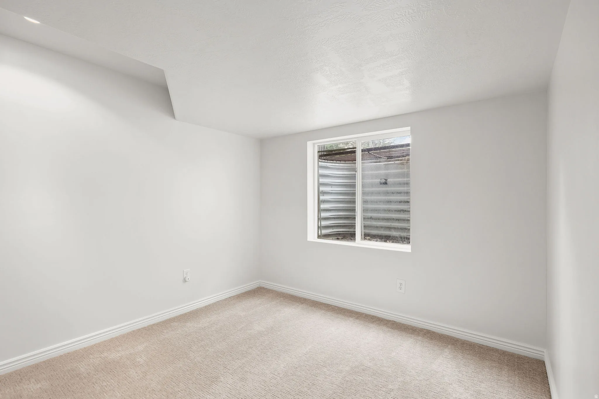Spare room featuring light carpet and baseboards