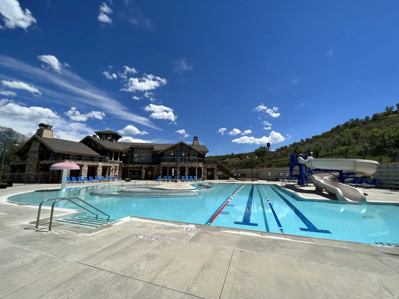 Community pool featuring a water slide, a water play area, and a patio area