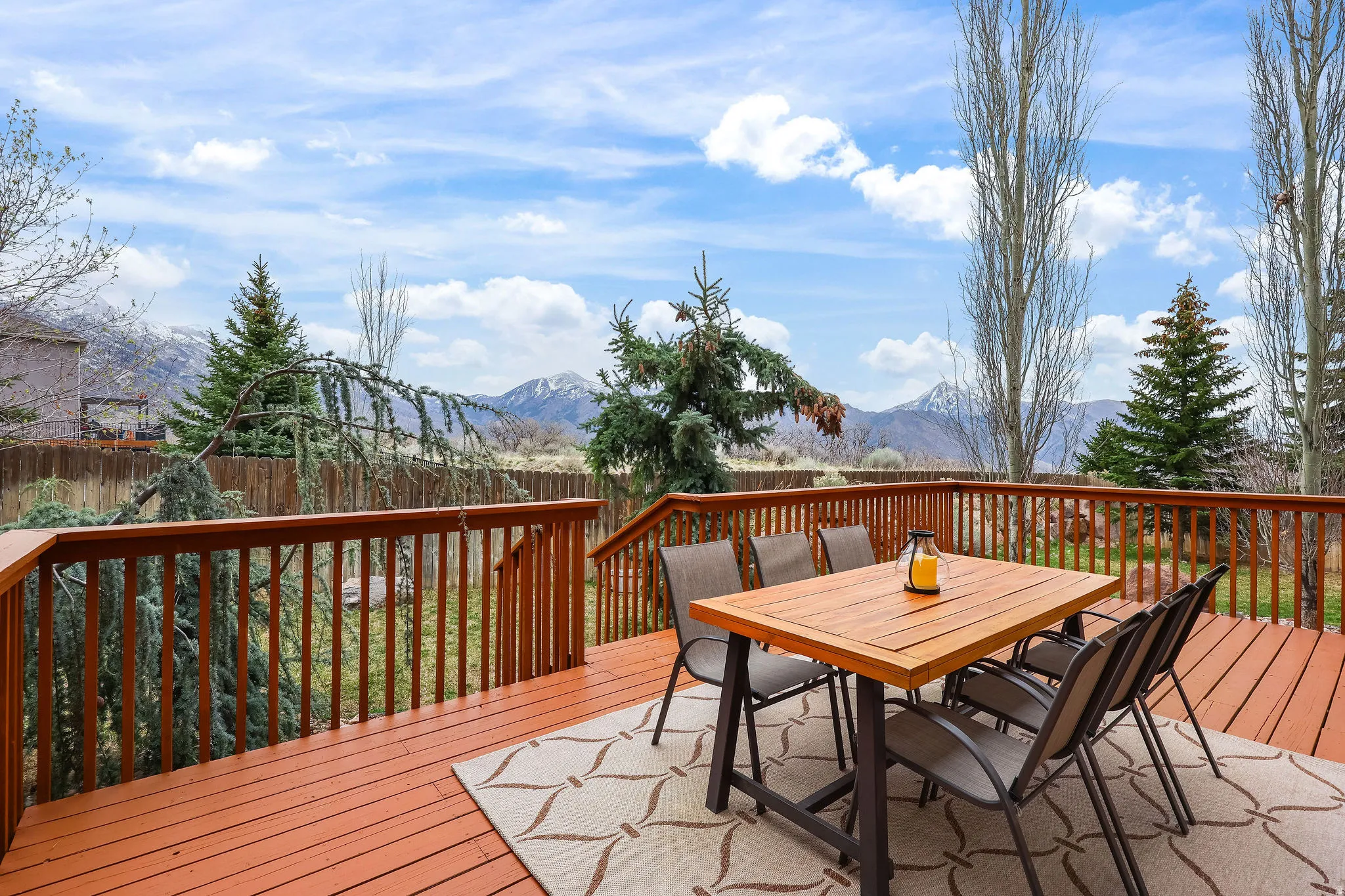 Wooden terrace featuring outdoor dining space, a mountain view, and a fenced backyard