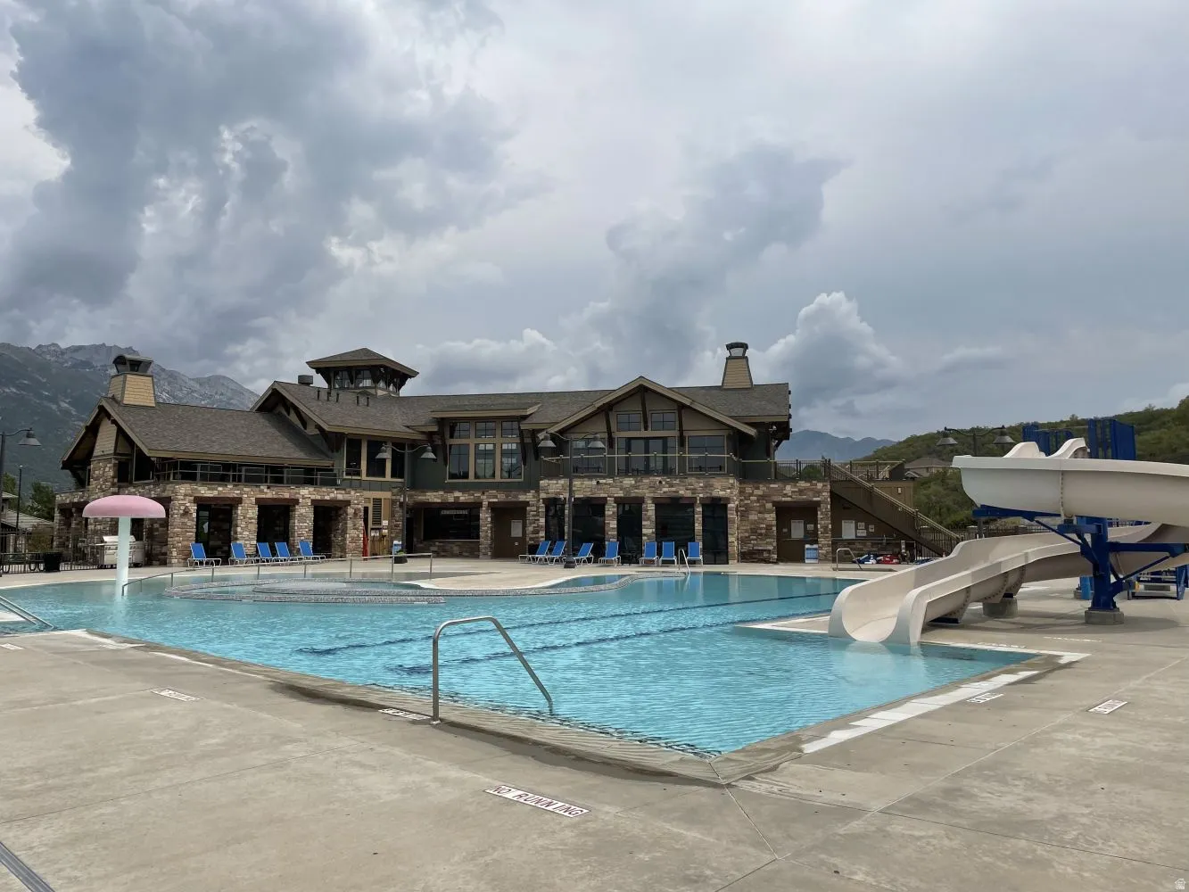 Community pool with a water slide, a patio, a mountain view, and a water play area