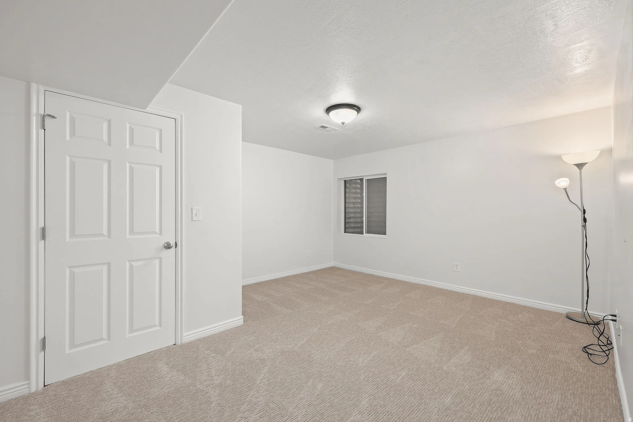 Unfurnished room featuring light carpet and a textured ceiling