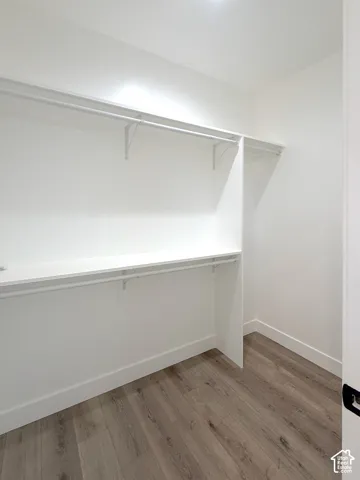 Built-in white shelving, integrated hanging rods, and wood-finish flooring