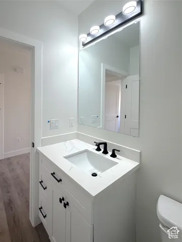 White vanity with shaker-style cabinetry, a white countertop, an undermount sink, and matte black hardware and faucet