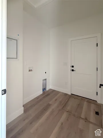 Wood-finish flooring throughout, white interior doors with black hardware, and wall-mounted electrical panel