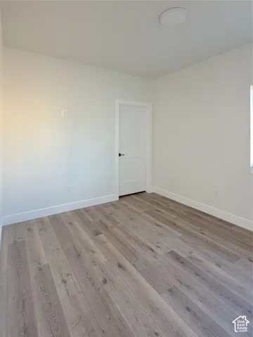 Light-toned wood-finish flooring, white walls, and a contemporary flush-mount ceiling light