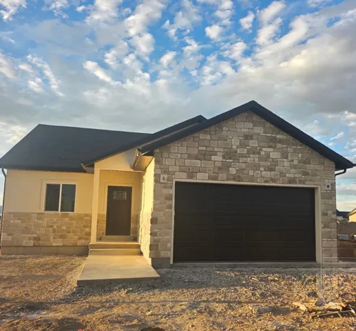 Stone and stucco exterior with a dark asphalt shingle roof