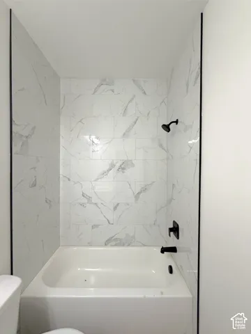 Built-in bathtub with a tile surround, featuring matte black fixtures and a wall-mounted shower head