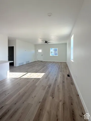 Expansive open-concept living space featuring wood-finish flooring, recessed lighting, and a ceiling fan