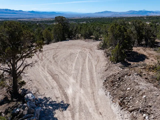 Expansive cleared building site featuring mature trees and distant mountain ranges