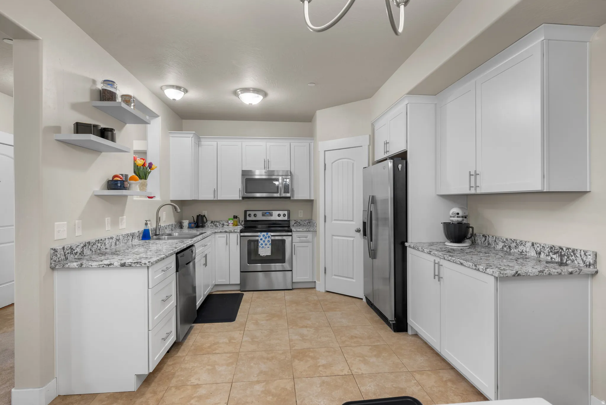 Kitchen with open shelves, stainless steel appliances, white cabinetry, light tile patterned floors, and granite stone counters