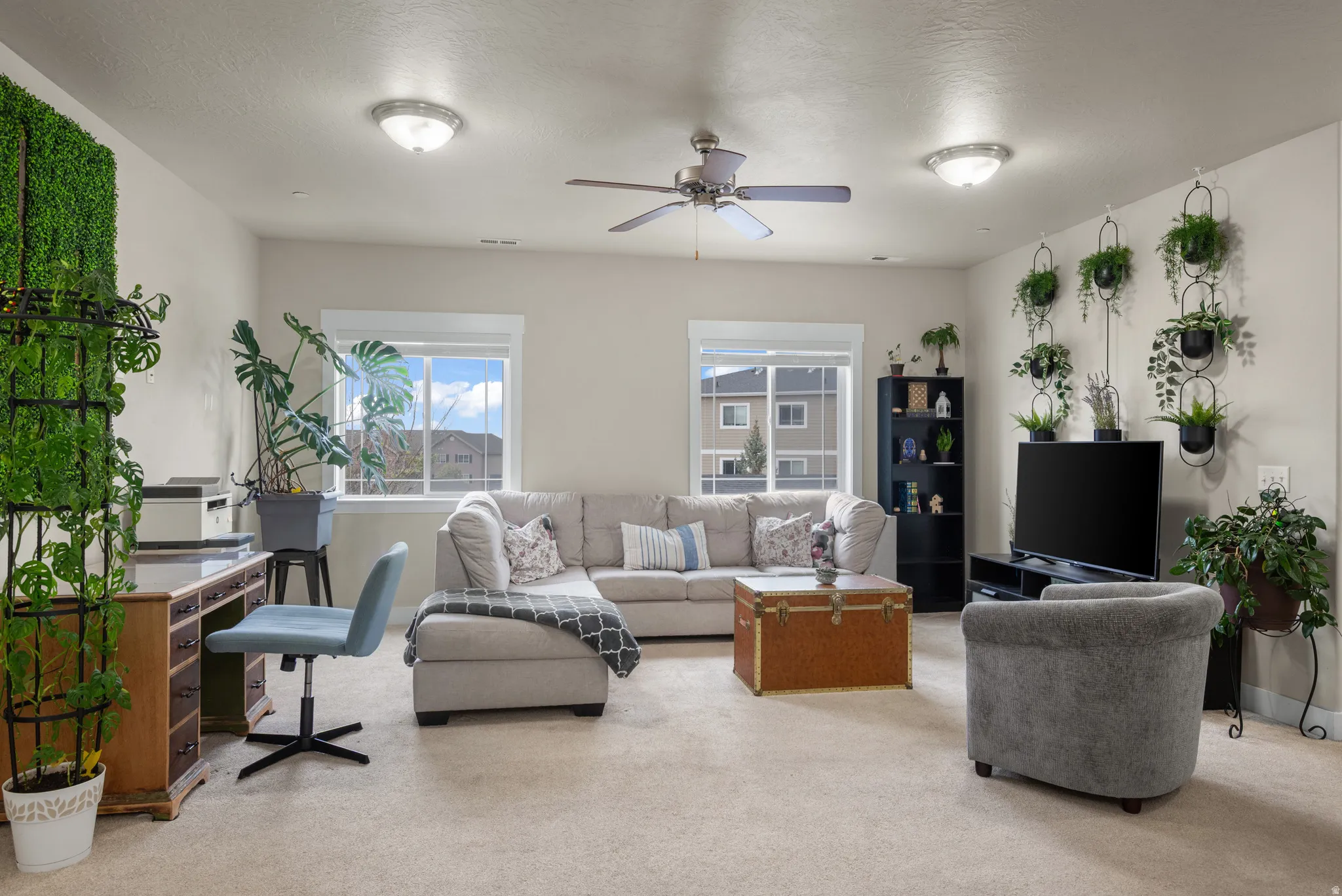 Carpeted living area with a ceiling fan and baseboards
