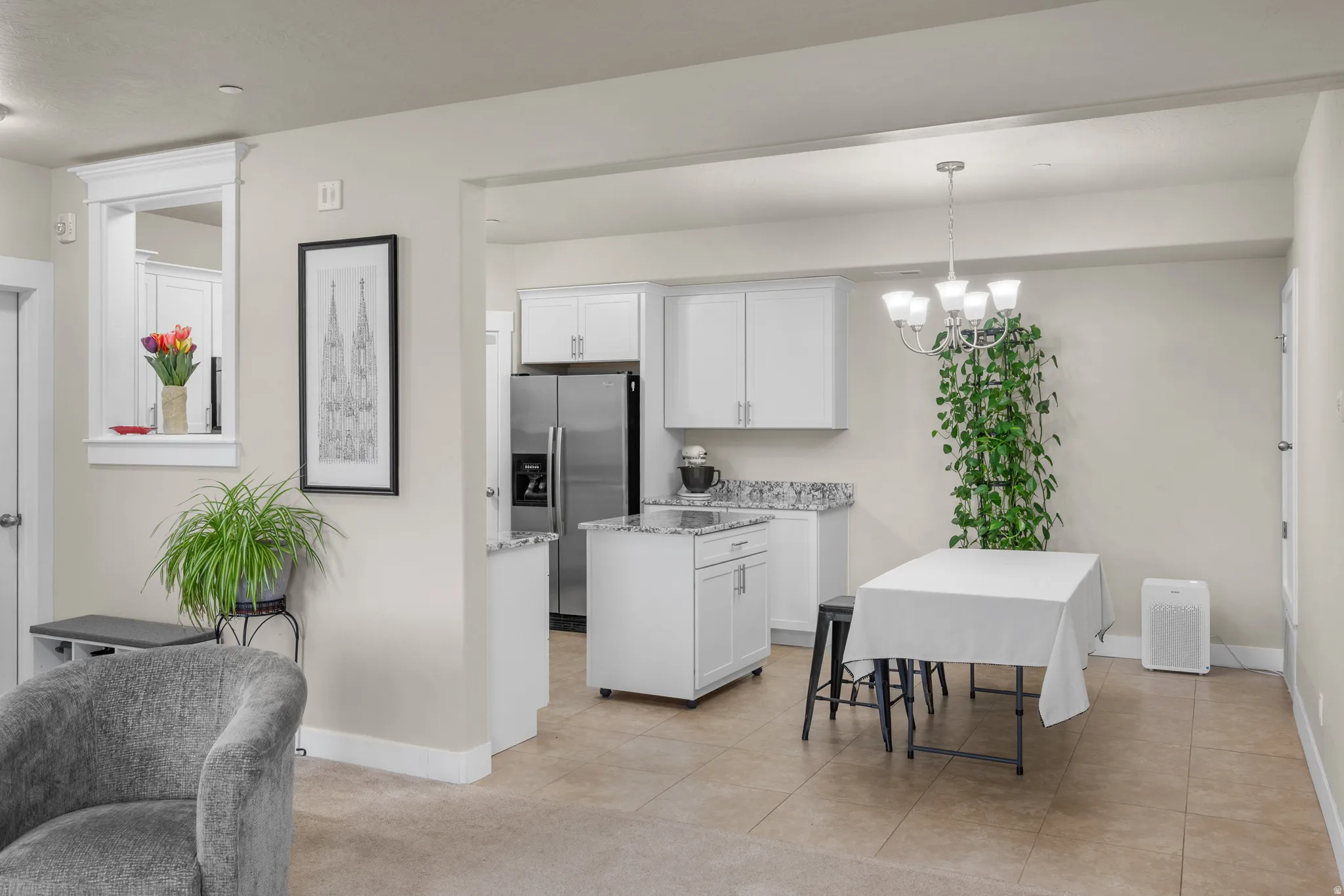 Kitchen featuring white cabinets, stainless steel refrigerator with ice dispenser, granite stone counters, and light tile patterned floors