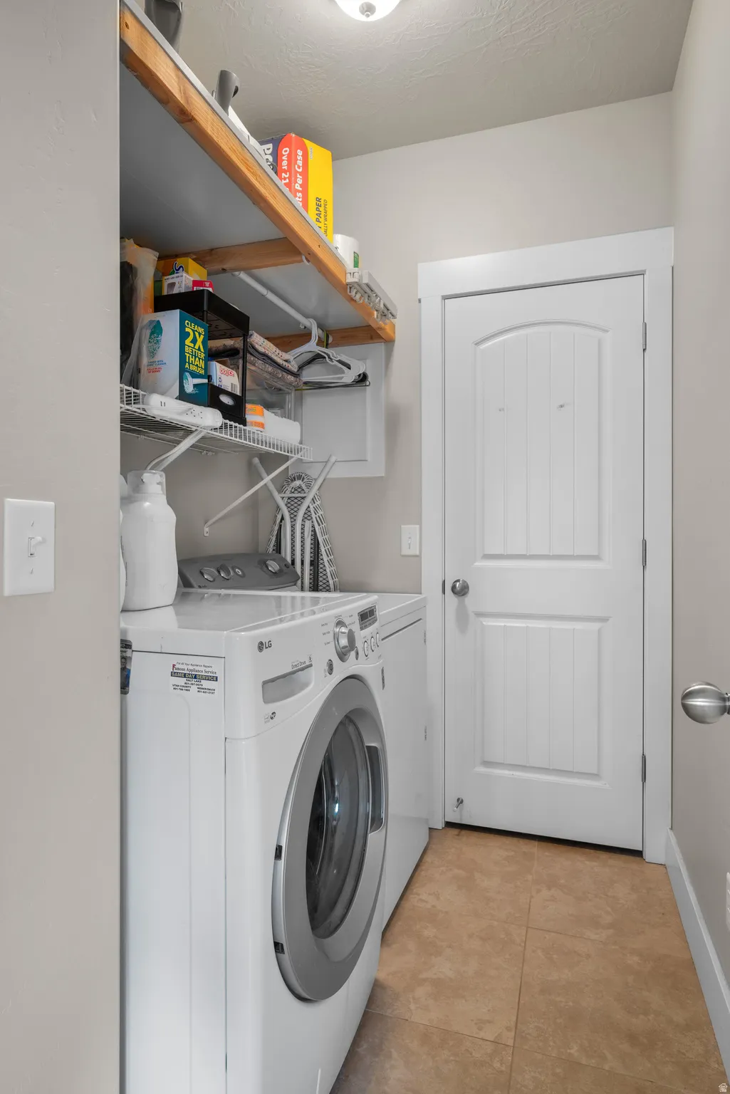 Laundry area with independent washer and dryer and light tile patterned floors