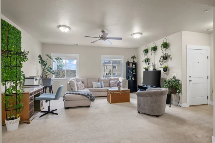 Living area featuring light carpet, a ceiling fan, an office area, and a textured ceiling