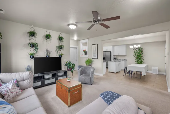 Living room with ceiling fan, light carpet, and suspended lighting
