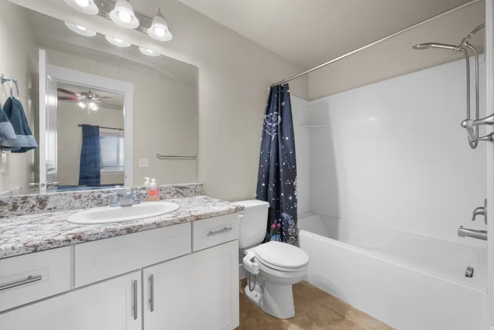 Full bathroom with vanity, shower / bathtub combination with curtain, a ceiling fan, and light tile patterned floors