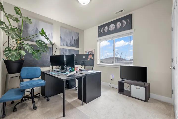 Home office with light colored carpet and baseboards