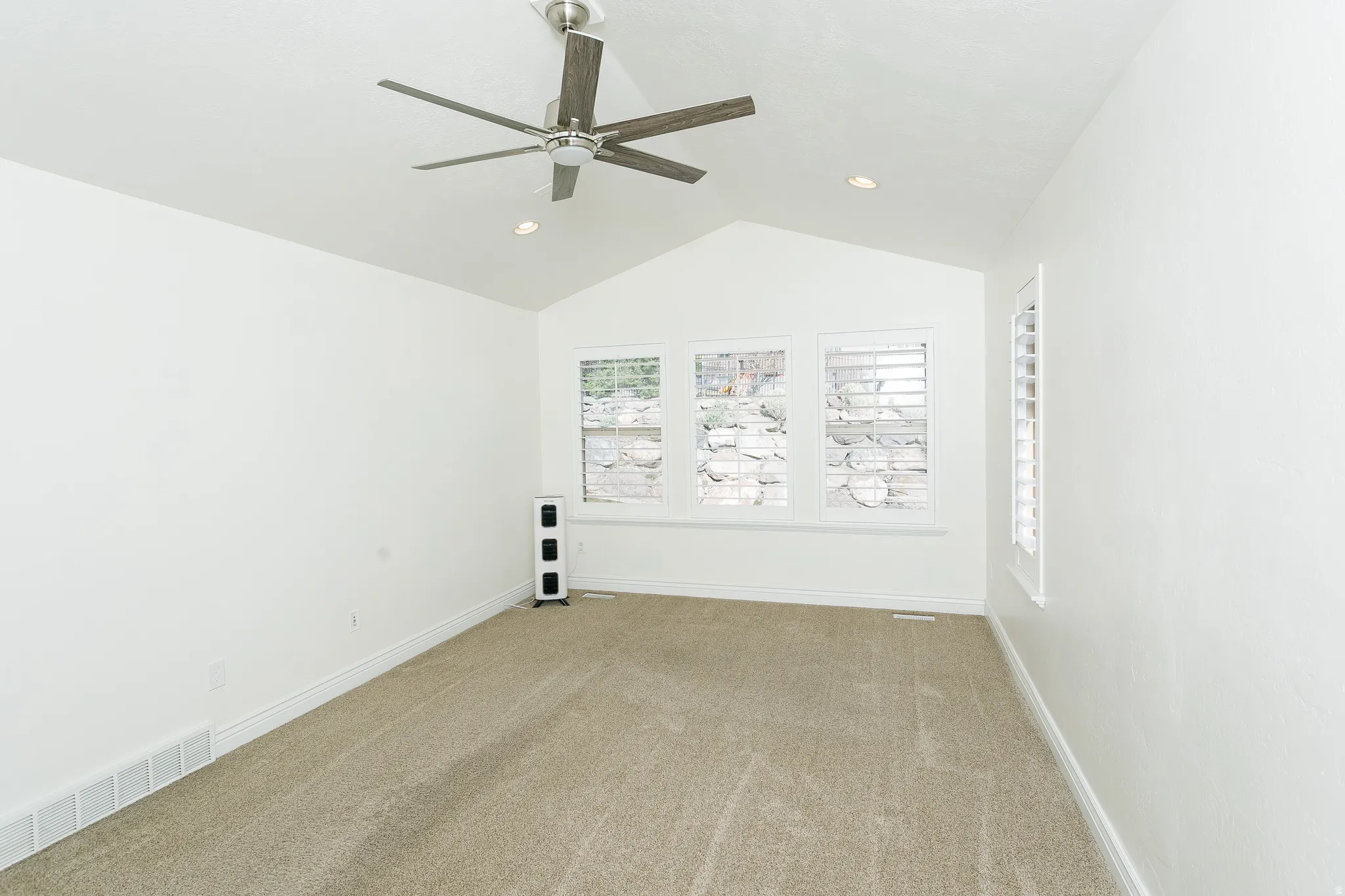 Spare room with carpet floors, a ceiling fan, and lofted ceiling
