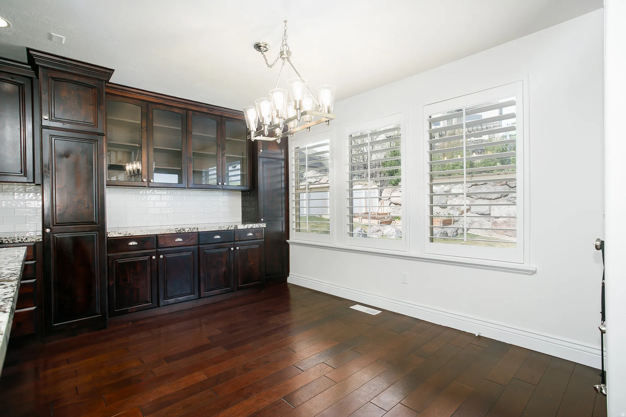 Unfurnished dining area featuring dark wood finished floors and hanging lights