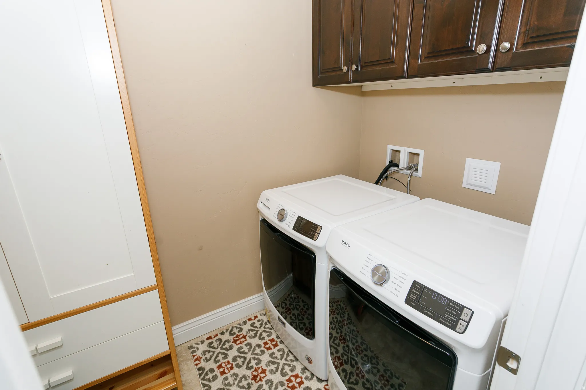 Laundry room with cabinet space, washer and dryer, and light tile patterned floors