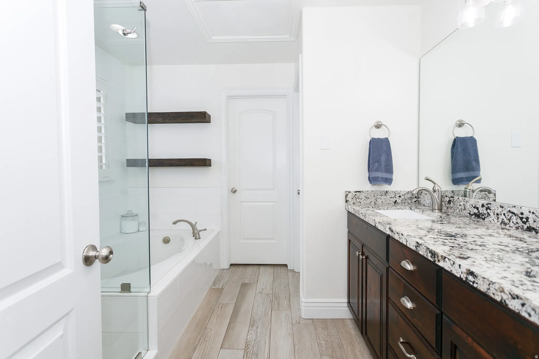 Full bathroom featuring vanity, light wood-style flooring, and a bath