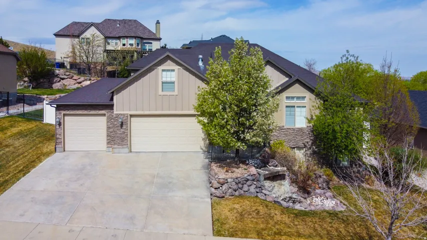 View of front facade with stone siding, concrete driveway, board and batten siding, and an attached garage