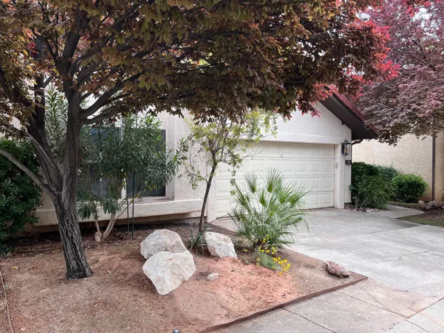 View of property exterior featuring concrete driveway, stucco siding, and an attached garage