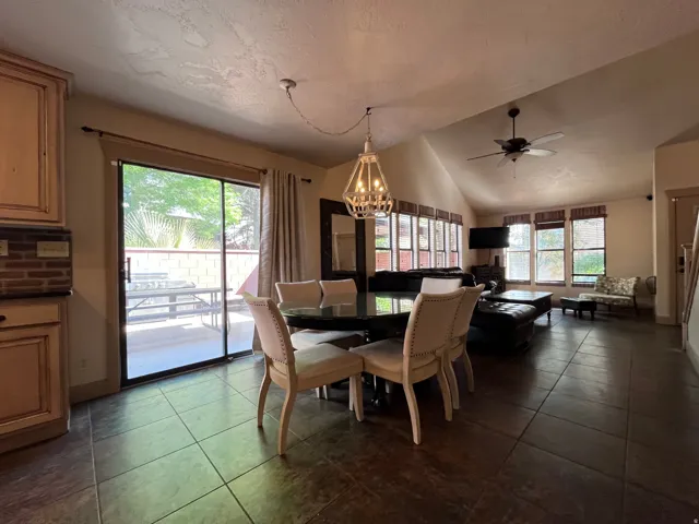 Dining space with a chandelier, a ceiling fan, plenty of natural light, dark tile patterned flooring, and lofted ceiling