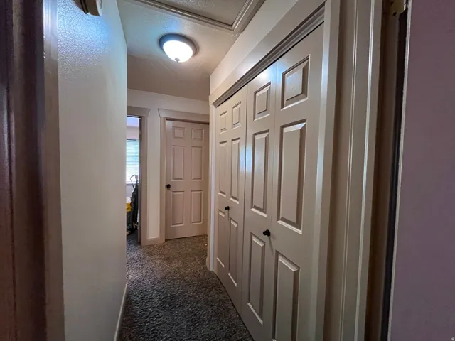 Hallway featuring dark colored carpet and a textured ceiling