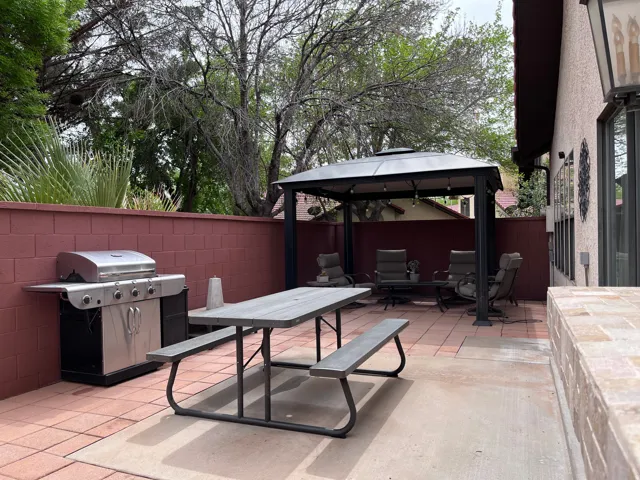 Fenced backyard featuring a gazebo, a patio area, and a grill