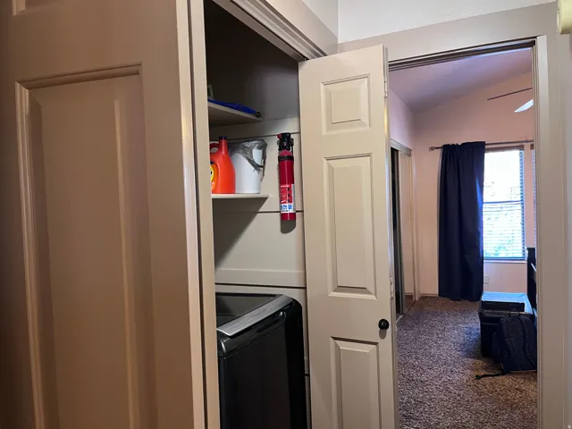 Laundry area featuring vaulted ceiling, washer / dryer, and carpet floors