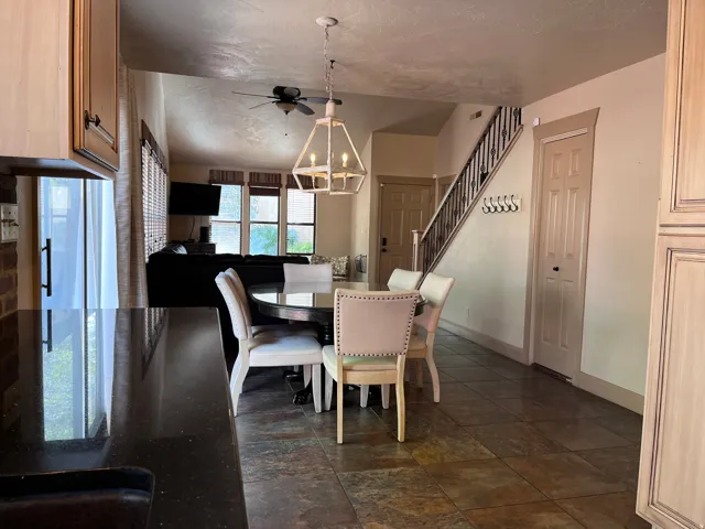 Dining room with dark stone finish flooring, hanging lights, and ceiling fan