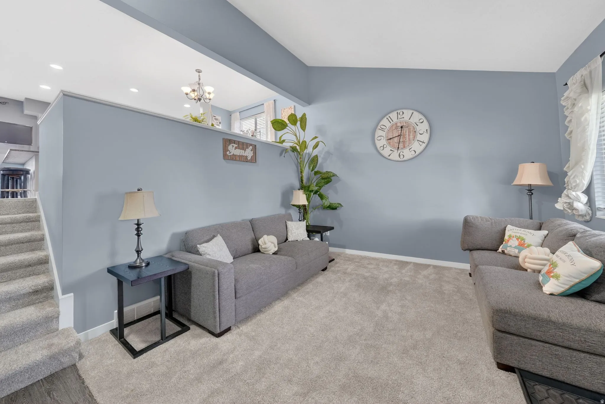 Living area with light carpet, vaulted ceiling, and a chandelier