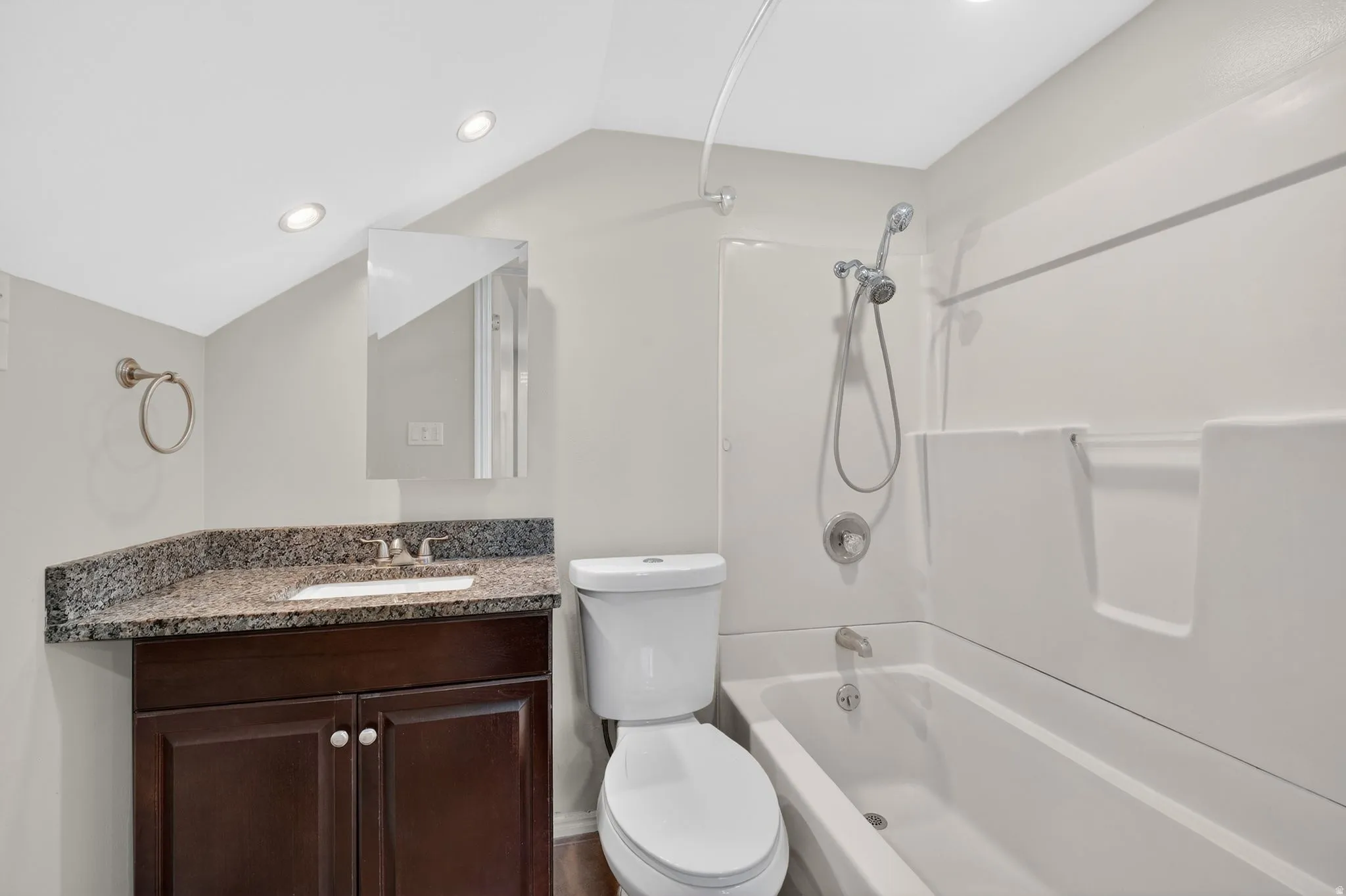 Bathroom featuring vanity, shower / tub combination, lofted ceiling, and recessed lighting