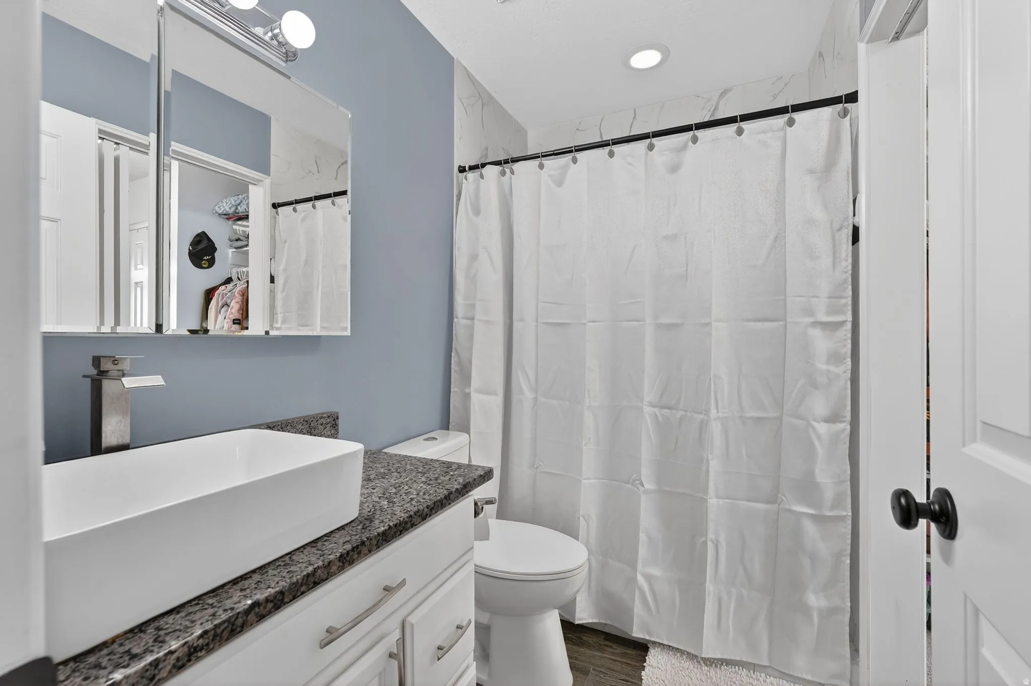 Full bathroom featuring vanity, a shower with curtain, and dark wood-style floors